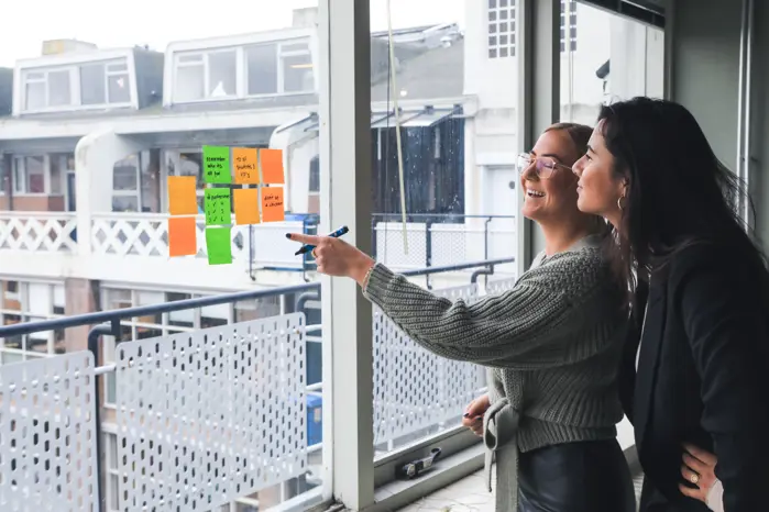 two female employees discussing and brainstorming with sticky notes