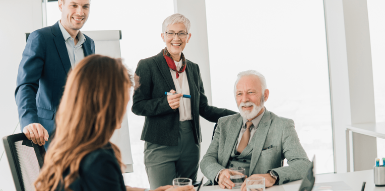 a group of employees of diverse ages and genders around a meeting table