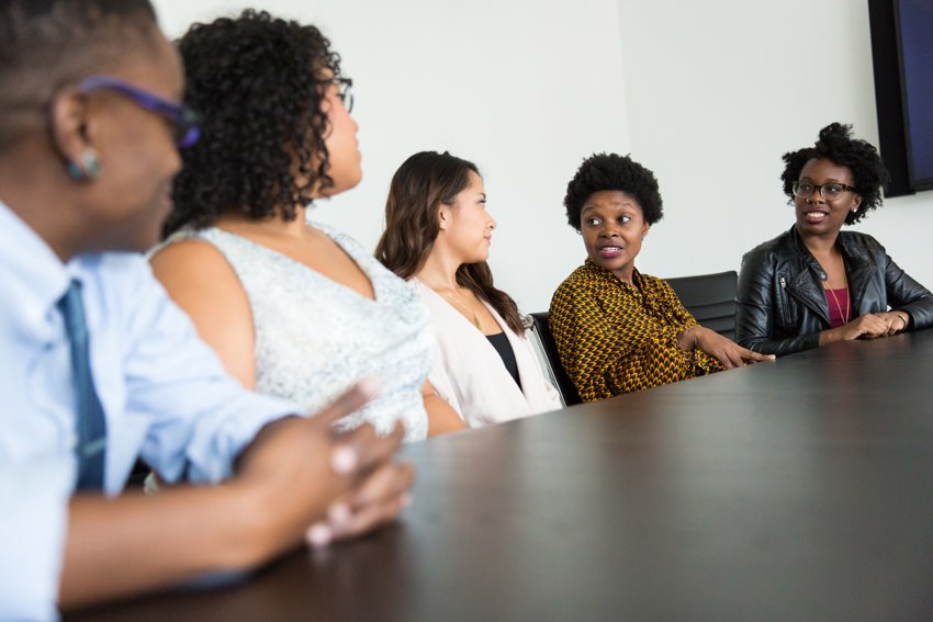 A group of people sitting having a conversation in a meeting style