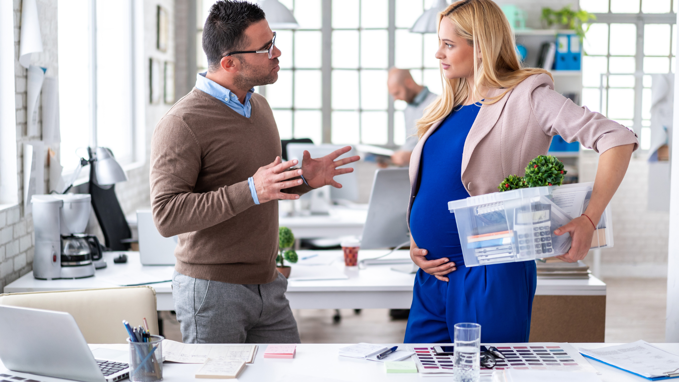 male talking to pregnant female work colleague in an office